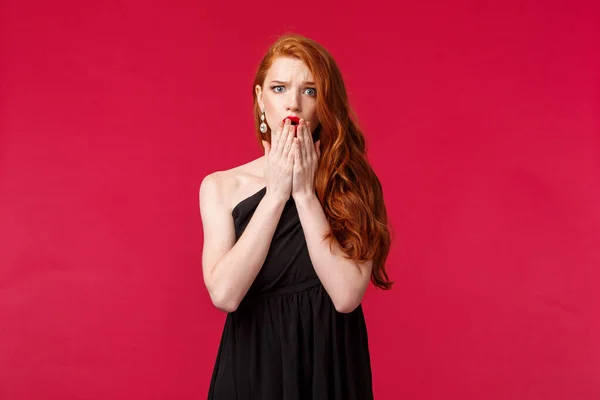 Concepto de moda, lujo y belleza. Retrato de mujer sorprendida y preocupada, joven preocupada con el pelo de jengibre, vestido negro, ver cosas malas sucedió en la fiesta, jadeando y frunciendo el ceño alarmado —  Fotos de Stock