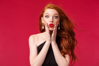 Makyaj, güzellik ve kadın konsepti. Şaşırmış, nutku tutulmuş ve etkilenmiş kızıl saçlı kadının yakın plan portresi dedikoduyu öğrendi, yanaklarına dokundu ve inançsız kameraya baktı.