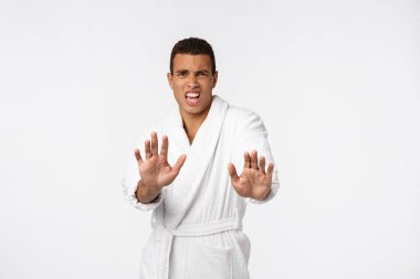 Portre şoku ve canı sıkkın genç adam elini kaldırdı. Durmak yok demek için orada duruyor. Gri arka plan.