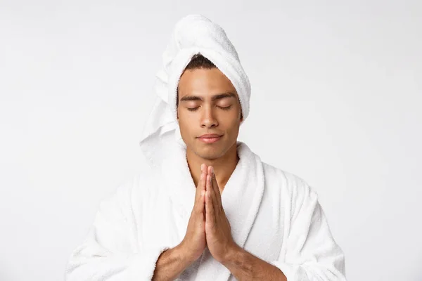 Sakin, yakışıklı Afrikalı adam dua ediyor. El ele tutuşup meditasyon yapan ciddi, barışçıl genç bir adam. İnanç kavramı — Stok fotoğraf