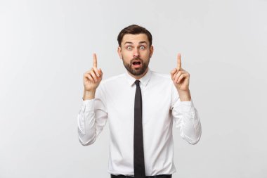 Genç yakışıklı iş adamı parmağını kullanarak bir şeyi işaret ediyor. Beyazda izole edilmiş
