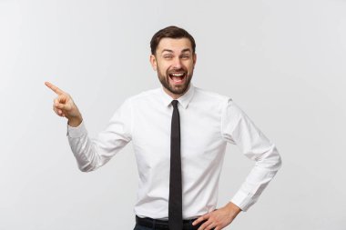 Genç yakışıklı iş adamı parmağını kullanarak bir şeyi işaret ediyor. Beyazda izole edilmiş