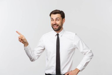 Genç yakışıklı iş adamı parmağını kullanarak bir şeyi işaret ediyor. Beyazda izole edilmiş