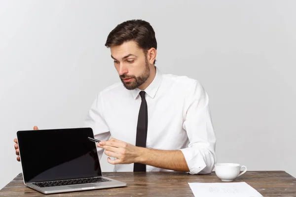 Geschäftsmann, der am Schreibtisch sitzt, zeigt mit dem Finger auf einen isolierten weißen Laptop-Bildschirm mit leerem Kopierraum, schöner junger Geschäftsmann. — Stockfoto