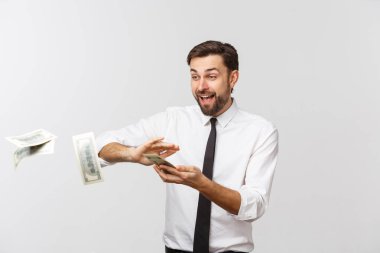 Mutlu genç bir iş adamının portresi. Gri arka planda izole edilmiş para banknotları atıyor..