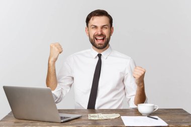 Mutlu heyecanlı adam, gri arka planda izole bir sandalyede oturmuş zaferi kutluyor..