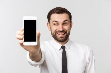 Çekici genç iş adamı beyaz arka planda boş cep telefonu gösteriyor