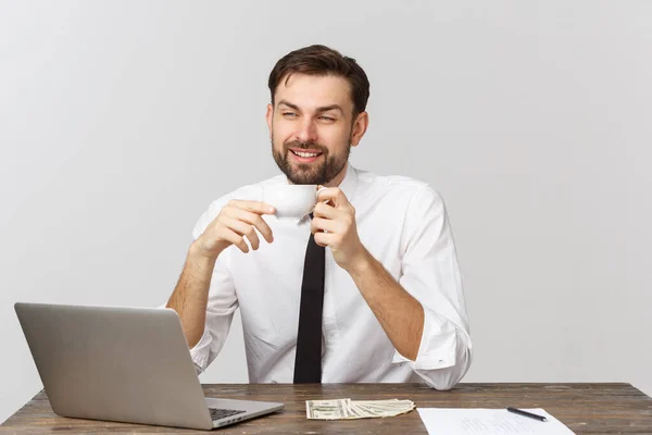 Geschäftsmann im weißen T-Shirt, Kaffee trinkend, am Tisch mit Laptop und Smartphone. Tagesgeschäft — Stockfoto