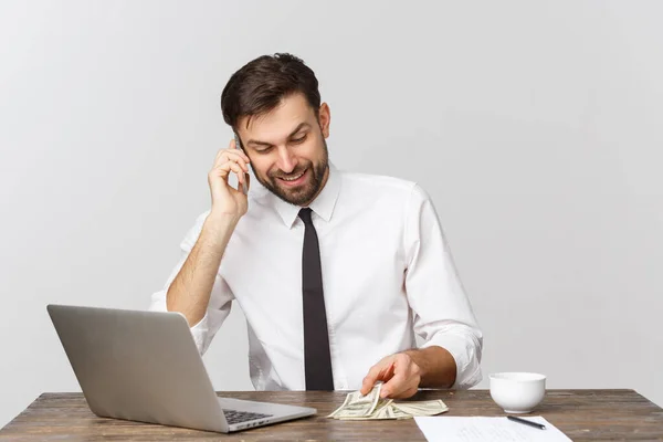 Portrait d'un homme souriant parlant sur un téléphone portable, assis au bureau, regardant l'écran de l'ordinateur — Photo