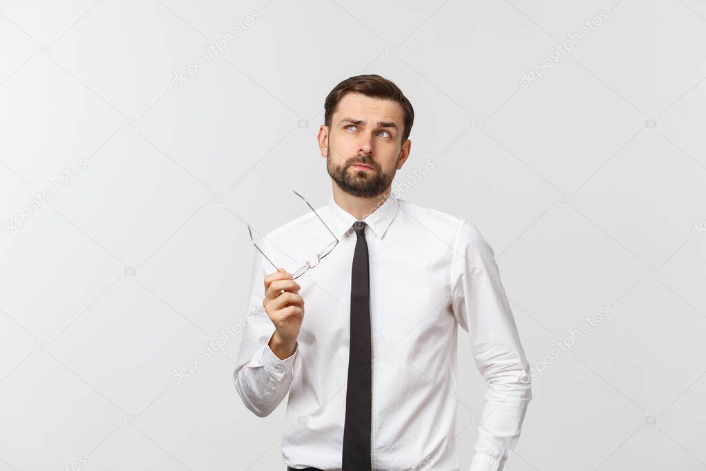 A handsome young Caucasian millennial man in glasses and a white T-shirt isolated on a gray studio background, looks at blank copy.