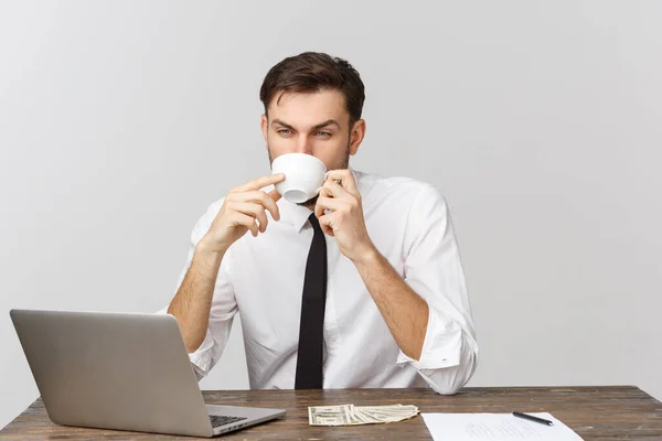 Empresario en una camiseta blanca bebiendo café sentado en la mesa con portátil y smartphone. Rutina diaria de negocios — Foto de Stock