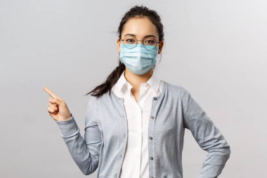 Covid19, virüs, sağlık ve tıp konsepti. Tıbbi maskeli, ciddi görünümlü Asyalı bir kızın portresi, Coronavirus ve gribi önler, solu gösterir, hastalıklar hakkında bilgi verir.