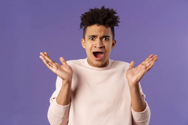 Portrait en gros plan d'un homme hispanique frustré, mécontent et dérangé, écartant les mains dans la consternation et la confusion, regardant la caméra bouleversée par une expression grimaçante déçue, un fond violet — Photo