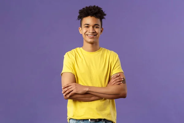 Κοντινό πλάνο πορτρέτο του αυτοπεποίθηση, έξυπνος και επαγγελματίας νεαρός φοιτητής με τρόμο, κίτρινο t-shirt, σταυρώνουν τα χέρια πάνω από το στήθος και χαμογελώντας ευχαριστημένος, ξέρει τι κάνει, μωβ φόντο — Φωτογραφία Αρχείου