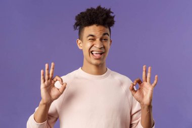 Kendine güvenen ve kaygısız genç bir adamın portresi rahatlayın diyor ve sorun yok, her şey kontrol altında, güvence altında, tamam işaretleri göster, en iyi kaliteyi garanti et, iyi teslimat servisi