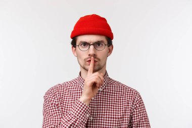 Ciddi sinirli, sakallı, beyaz bir adam kameraya şşşş yapıyor. İtaatsiz öğrencilerin yüksek sesle konuşmasından hayal kırıklığına uğruyor ve sinirleniyor. Sessiz ol.