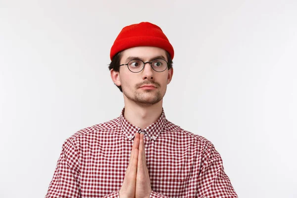 Närbild porträtt rolig kaukasisk man med mustasch, röd mössa och glasögon, göra namaste eller be gest titta bort med allvarliga beslutsamma uttryck, stående vit bakgrund — Stockfoto