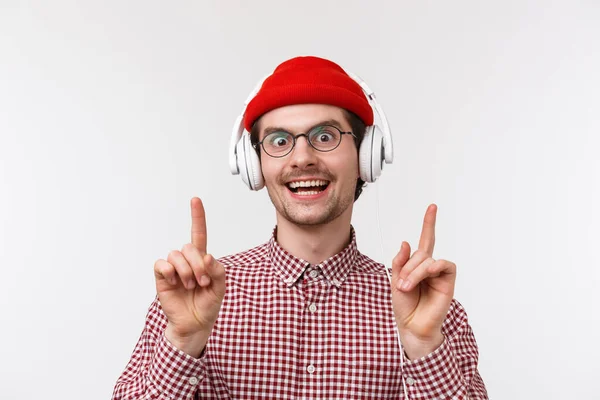 Muzyka, technologia i koncepcja ludzi. Groovie uroczy brodaty mężczyzna w okularach i czerwonej czapce, taniec radośnie do fajnej piosenki, noszenie słuchawek i uśmiechnięty aparat wesoły, białe tło — Zdjęcie stockowe