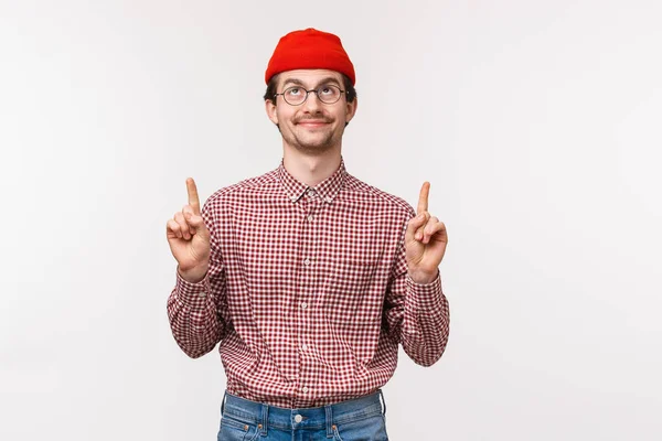 Midja upp porträtt nöjd söt skäggig kille i röd mössa och glasögon, tittar upp himlen njuter våren fin dag, hittade något coolt, peka och titta upp, ler mot toppen reklam — Stockfoto