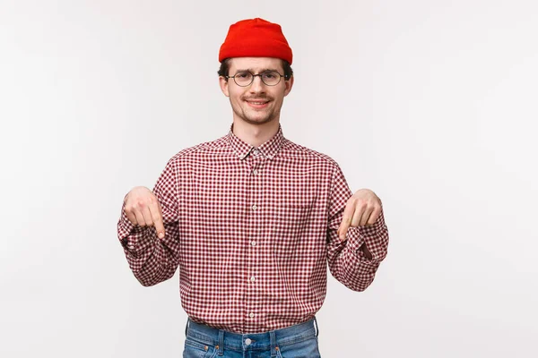 Midjan upp porträtt skeptisk och tveksam oimponerad ung man i mössa och glasögon, grimace missnöjd uttrycka ogillar och besvikelse i senaste uppdateringen, pekar finger ner — Stockfoto