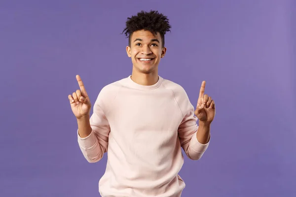 Waist-up portrait of dreamy, handsome 25s young hispanic man seeing good promotion, best deal or offer from online shop, pointing fingers top advertisement, looking up with satisfied smile — Stock Photo, Image