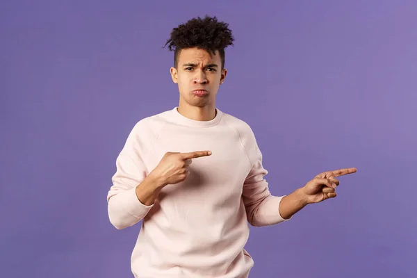 Portrait of gloomy, envy young man with dreads, frowning and pouting, making sad grimace while pointing fingers right at awesome thing he cant have, whining and complaning — Stock Photo, Image