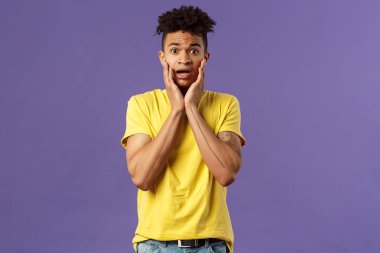 Hayır, ne yapayım? Endişeli, panikleyen genç adamın portresi endişeli ve kafası karışık, suratını tut ve soluk soluğa kal endişeli, dik dik bakan kamera alarmlı, mor arka plan