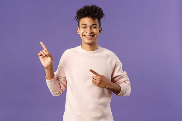 Portrait of cheerful, healthy smiling man pointing fingers upper left corner, recommending buy product, shop online, order delivery, advertisement and people concept, purple background — Stock Photo, Image