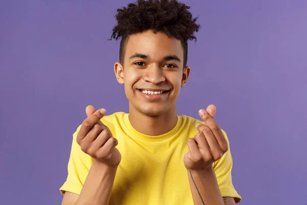 Retrato de cerca del encantador joven lindo con corte de pelo afro, mostrando signos del dedo del corazón coreano y sonriendo, expresar su amor y simpatía hacia la persona, de pie fondo púrpura —  Fotos de Stock