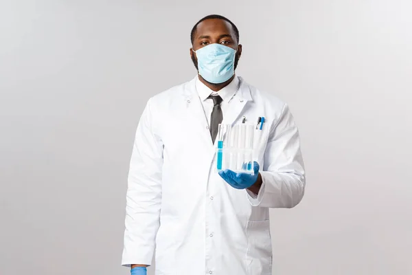Covid-19, coronavirus 환자 치료 및 실험실 개념. 심각하게 보이는 전문적 인 아프리카 계 미국인 의사 얼굴 마스크와 라텍스 장갑, 바이 얼스들고, 백신이든 시험관 — 스톡 사진