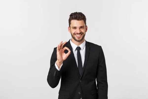 Schöner lächelnder Geschäftsmann zeigt Ok-Zeichen mit Fingern über grauem Hintergrund. — Stockfoto