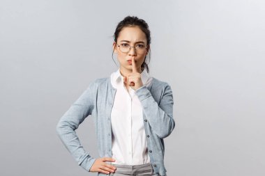 Eğitim, öğrenim ve online sınıf konsepti. Ciddi görünümlü genç Asyalı bayan öğretmen, ders sırasında sessizlik talep ediyor, kızgın suratla kameraya sus, sessiz ol.