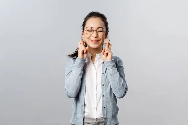 감정, 사람들 과 생활 방식의 개념입니다. 희망적 이고, 꿈같아 보이는 아시아인 소녀의 근접 한 눈 과 미소짓는 공상, 믿음의 소망 이 실현되는 꿈, 행운의 손가락을 교차하며, 회색 배경 위에서 기도 — 스톡 사진