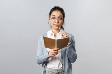 Eğitim, öğretmenler, üniversite ve okul konsepti. Düşünceli zeki Asyalı kız öğrenci ders çalışıyor, ödev hazırlıyor ya da not defterine ders yazıyor, planlama yapıyor, üzerinde düşünüyor.
