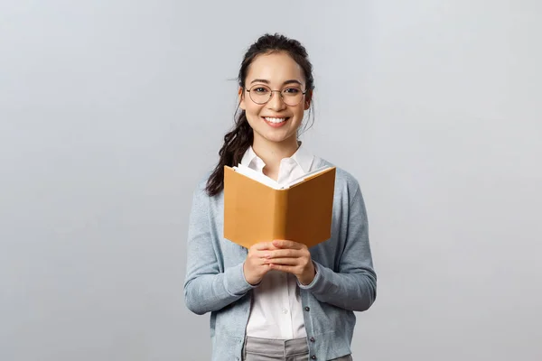 Éducation, enseignants, université et écoles concept. Jeune étudiante asiatique intelligente et créative lisant ses devoirs ou son poème, étudiant pour un test, tenant un planificateur ou un cahier, une caméra souriante — Photo