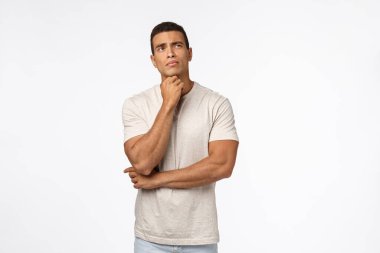 Kararsız genç, düşünceli erkek atlet zor bir seçim yapmaya çalışıyor, ne yapacağına karar veriyor, çeneye dokunuyor, sorunlu, düşünceli, cevapları arıyor, beyaz arka planda durup düşünüyor.