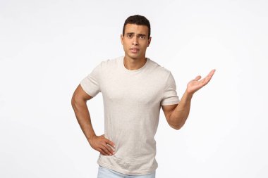 Şaşırmış genç, kafası karışmış yakışıklı erkek arkadaş. Ne olduğunu bilmiyor. Bir elinizi korku içinde kaldırın, kaşlarını çatarak ve şaşı bakarak, anlayamayarak, hayal kırıklığına uğramış beyaz arka planda durarak.