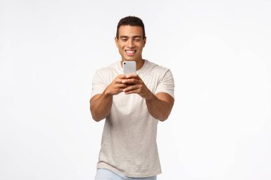Neşeli, heyecanlı, güçlü kasları olan, akıllı telefon tutan, hevesli bir cihaz gibi görünen, video kaydeden, eğlenceli bir etkinliğe katılan, telefon kamerasıyla fotoğraf çeken yakışıklı Brezilyalı bir adam.