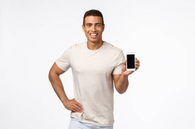 Gururlu ve iddialı tişörtlü, elinde akıllı telefon tutan, başvuru ya da alışveriş sitesini destekleyen, gülümseyen, tavsiye veren, reklam aleti ya da uygulaması olan, beyaz arkaplan