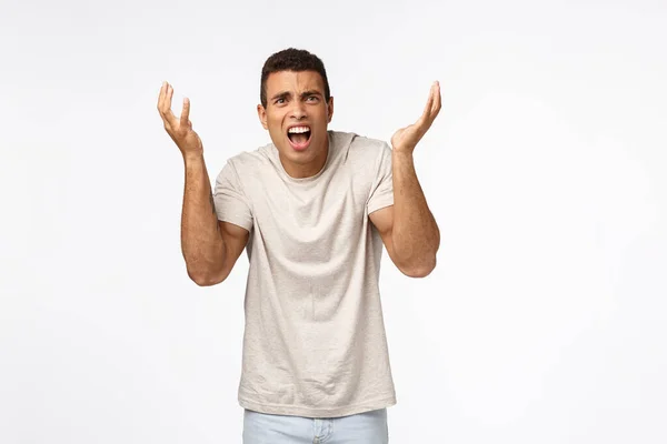 Déçu et paniqué, dérangé bel homme en t-shirt, levant les mains vers le haut frustré et mécontent, argumentant, se plaignant de l'échec injuste, perdre la concurrence, debout bouleversé fond blanc — Photo