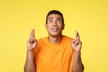 Endişeli umutlu adam yalvarıyor, yalvarıyor, dualar gerçek oluyor, dua ediyor, dua ediyor, şans diliyor, iyi şanslar diliyor, yarışmayı kazanmak istiyor, piyangoya bahis oynuyor, mucizeyi bekliyor, sarı arka plan