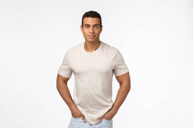 Kısa saçlı, kaslı, yakışıklı, kaslı, kaslı, kot pantolon cebinde el ele tutuşan, gülümseyen kamera beyaz arka planda duran, güvenilir, samimi bir yüz ifadesi olan bir adam.