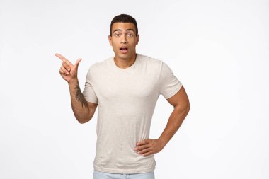 Kolunda dövmesi olan, şaşırmış, yakışıklı, bronz tenli, sıradan tişörtler giyen, yeni ürünü tartışırken nefes nefese kalan, sol tarafa bakan kamerayı işaret eden, tanıtım hakkında detayları öğrenmek isteyen bir adam.