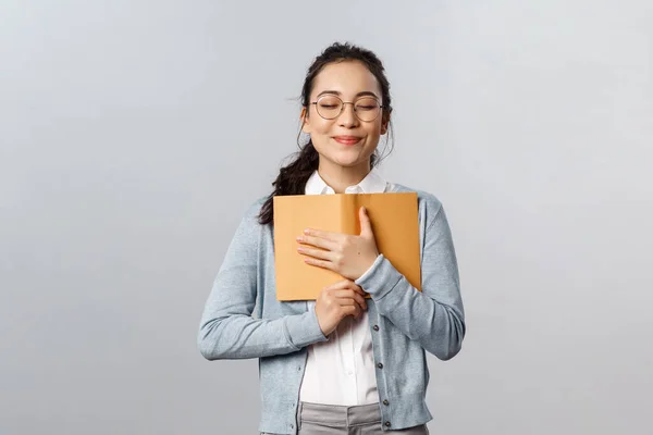 Éducation, enseignants, université et écoles concept. Romantique rêveuse mignonne yeux fermés féminins et câlins, appuyez sur son journal intime serré à la poitrine avec sourire optimiste, écrire sur son premier baiser heureusement — Photo