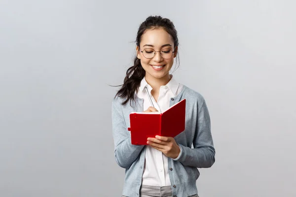 Concept d'enseignement, d'éducation et de style de vie universitaire. Sourire femme asiatique intelligente dans les lunettes, tuteur prendre des notes, se préparer pour les cours, écrire des conférences dans les cahiers, faire le calendrier dans le planificateur — Photo