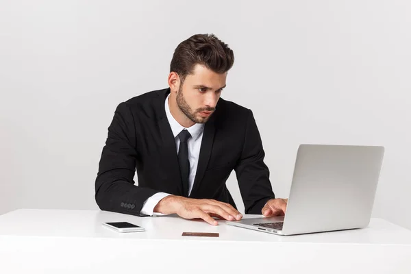 Seriöser gutaussehender Geschäftsmann, der im Büro arbeitet, Vorderansicht mit Laptop, isoliert auf weiß. — Stockfoto