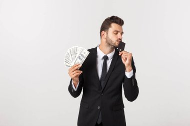 Elinde para dolu banknotlar ve beyaz arka planda izole edilmiş kredi kartı gösteren mutlu bir adamın portresi..