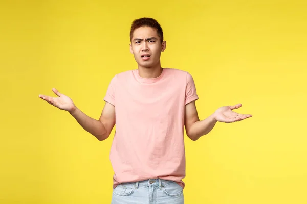 Whats masalah Anda manusia. Portrait of dishappy, frustarted young asian guy look bothered and confused, shrugging, spread hands sideways, cant understand what happened, stand yellow background — Stok Foto