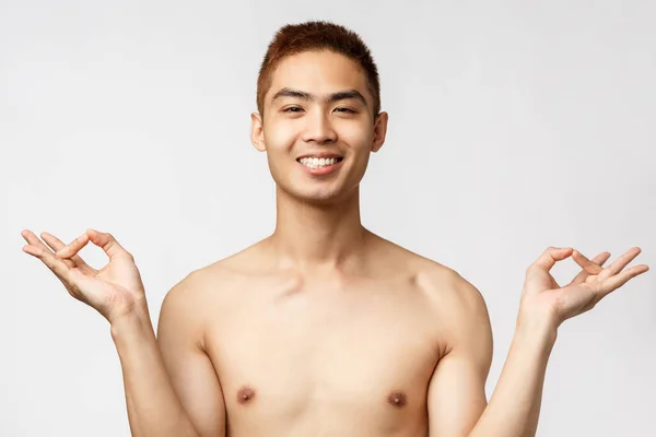 Krása, lidé a koncept domova. Klidný a uvolněný šťastný asijský muž stojící nahý nad bílým pozadím, usmívající se uvolněně a bez stresu, dosáhnout nirvány, dělat jógu, meditovat — Stock fotografie