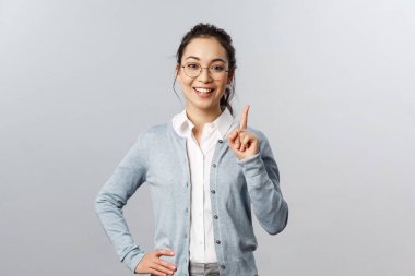 Eğitim, öğrenim ve online sınıf konsepti. Kural bir. Neşeli, güzel Asyalı kız egzersizi sınıfa anlatıyor, işaret parmağını kaldırıyor, işaret ediyor, bir öneri ekliyor ya da işaret ediyor, gülümsüyor.